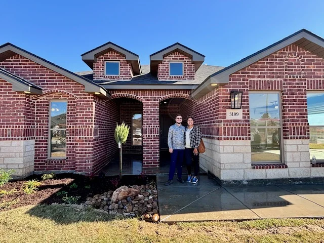 Home buyers standing outside their new brick home in the Texas Panhandle