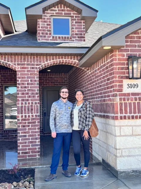 Happy home buyers smiling together on the porch of their new home